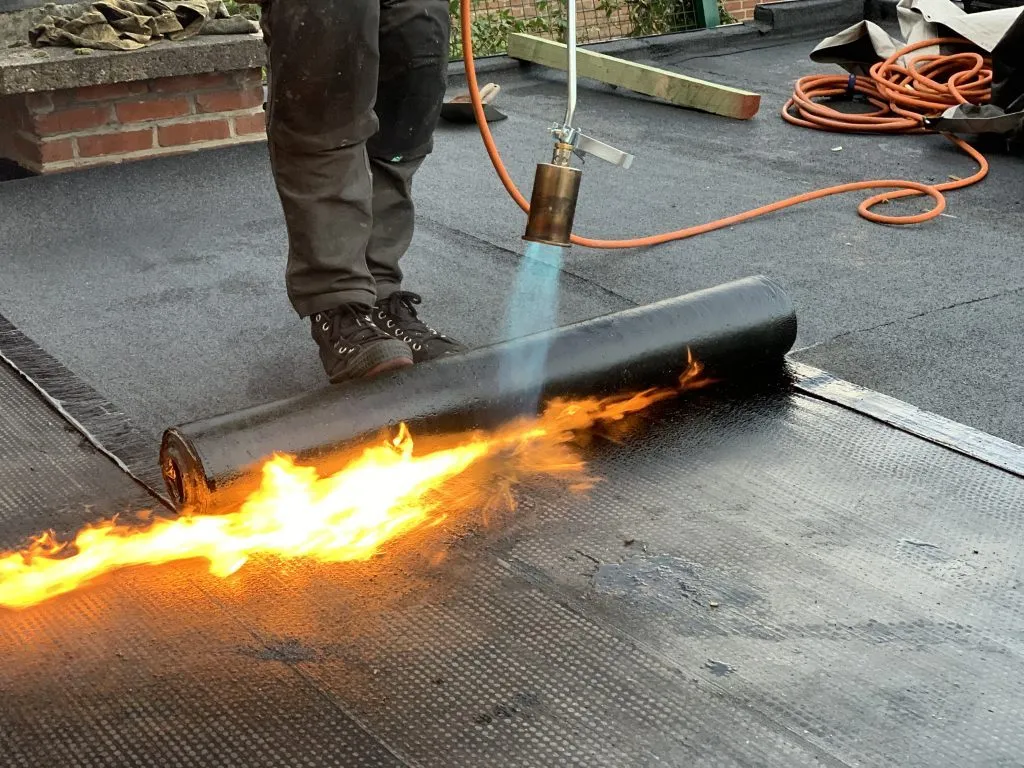 Bitumen dakbedekking wordt gebrand op een plat dak